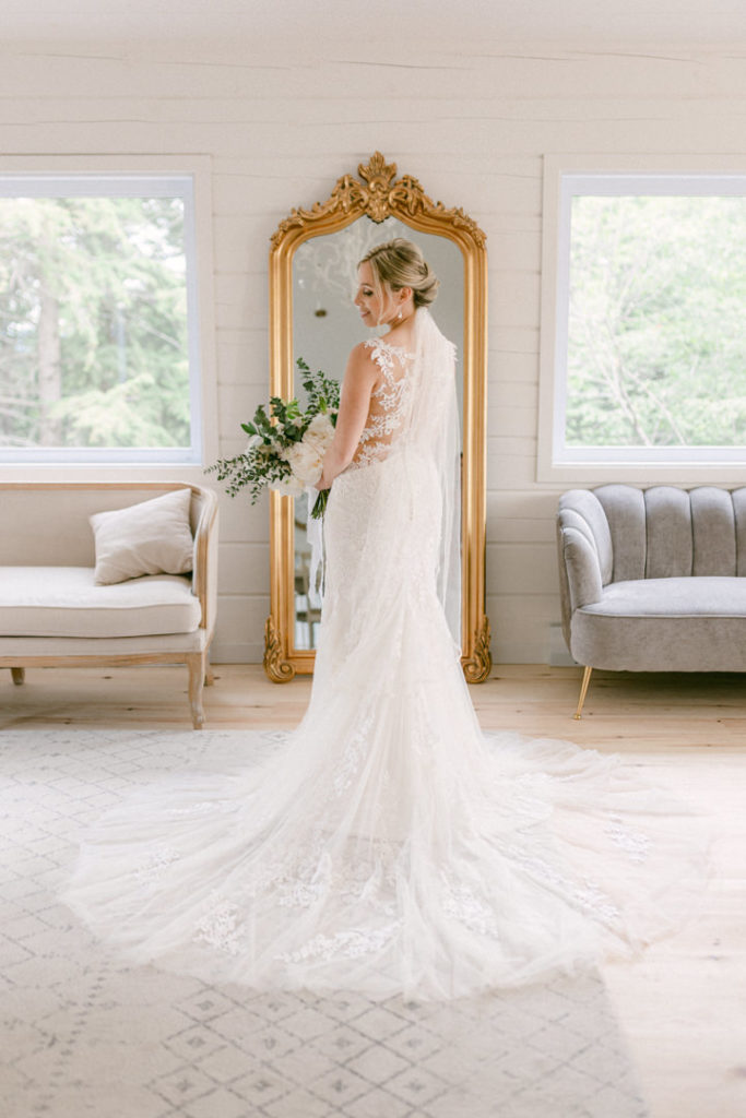 Gorgeous blonde bride holds her bouquet and takes in her final look in front of the mirror