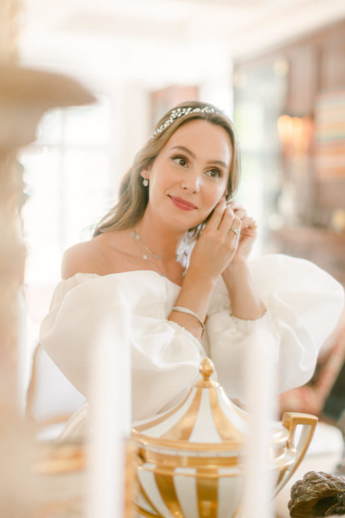 Bride smiles in the mirror at her reflection while getting ready for the big day
