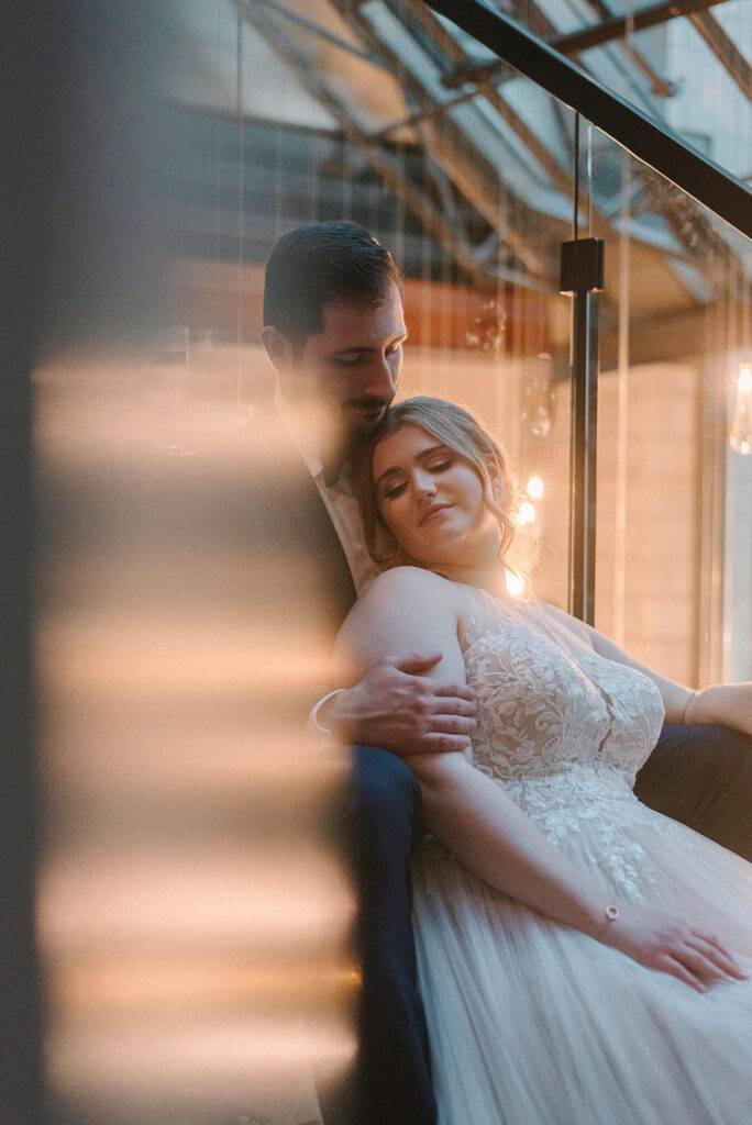 Groom looks at his new bride lovingly as she leans against him during their wedding at the William Gray Hotel