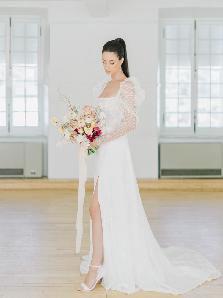 Bride stands in her puffy-sleeved dress holding her wedding bouquet in Montreal