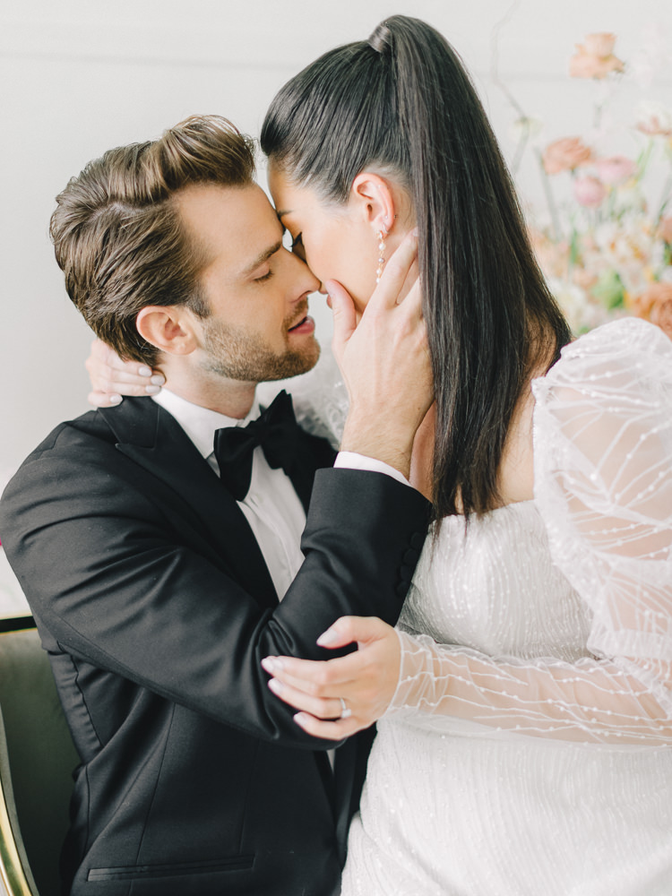Groom leans in for a kiss as his bride sits on his lap during their wedding in Montreal