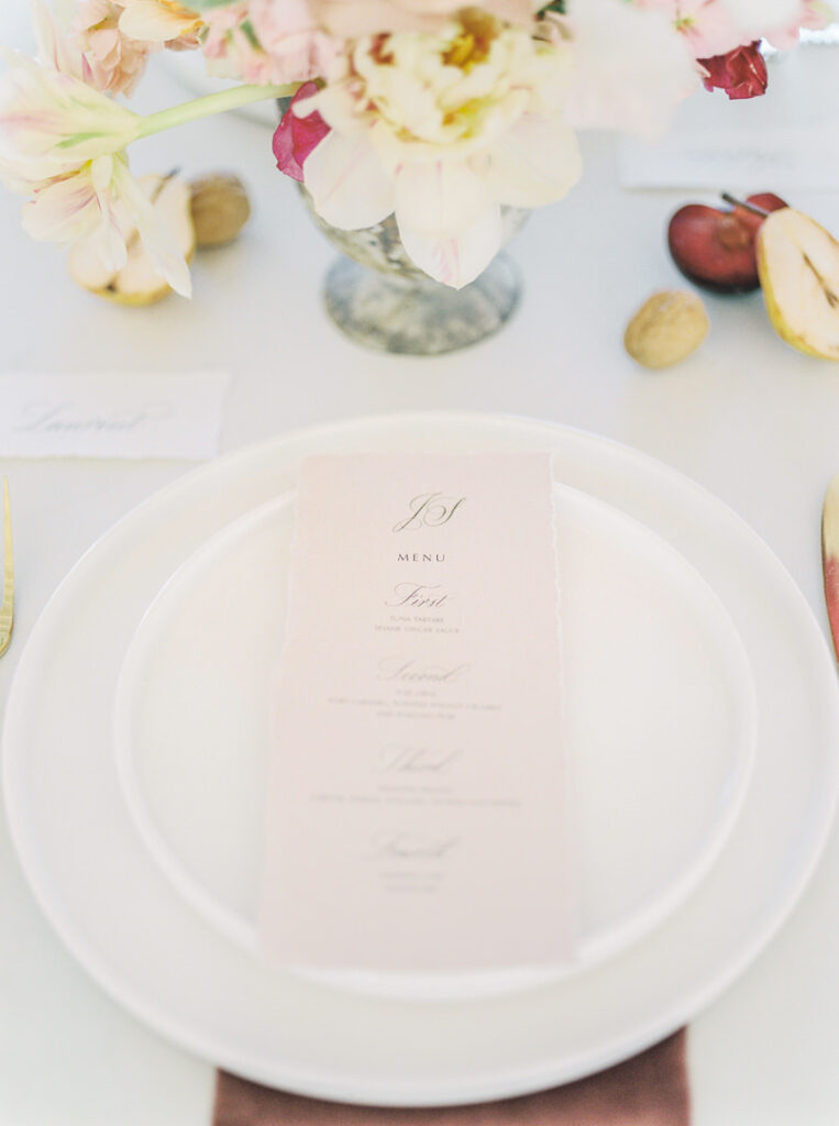 Table with a wedding menu in pastel colours accent the table flowers