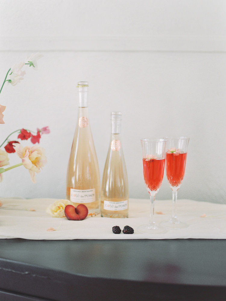 Champagne glasses filled next to bottles sit atop a side table at a wedding