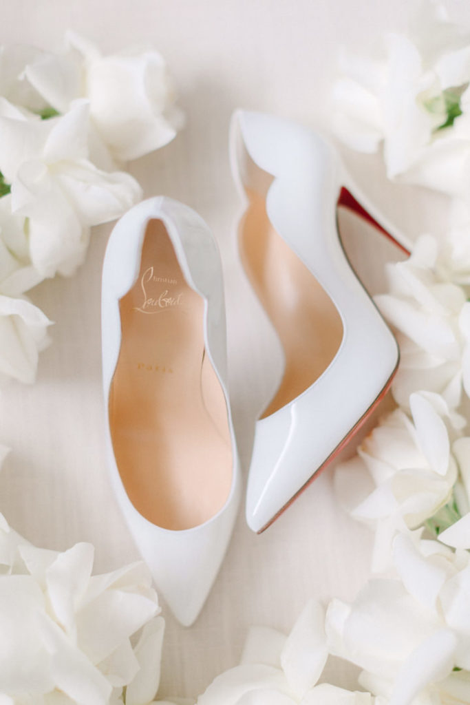 A classic stiletto by Louboutin chosen as wedding shoes photographed with white flowers surrounding them