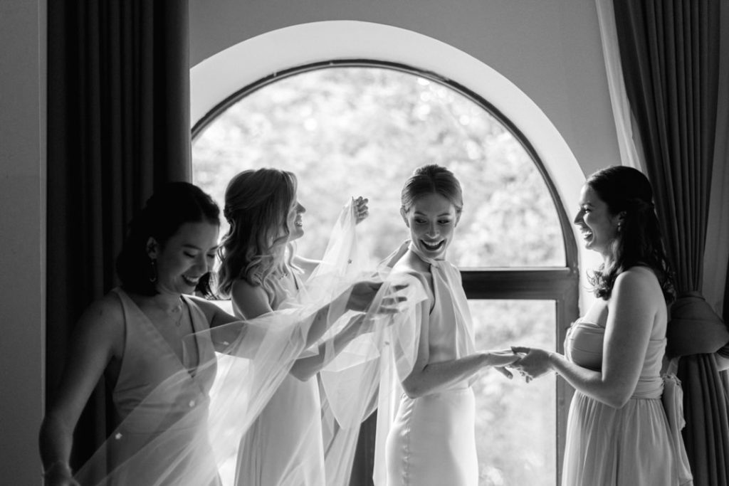 black and white photo of a bride getting ready for her wedding with her bridesmaids