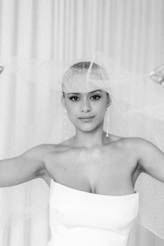 beautiful bride shows off her veil in a monochrome photo taken by a wedding photographer
