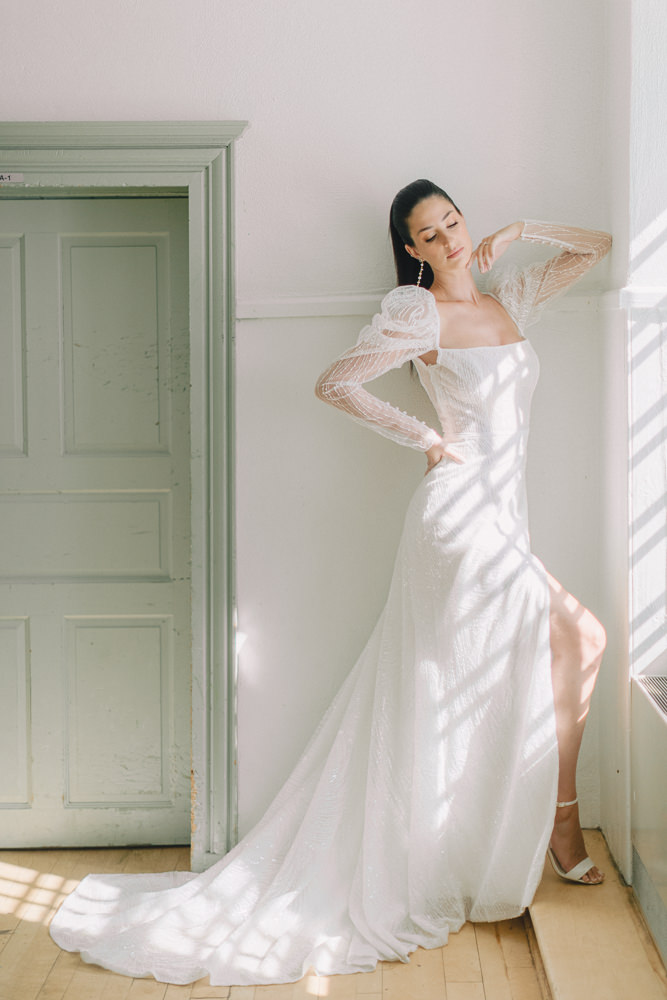 Beautiful dark haired bride poses like a model next to a window in Montreal