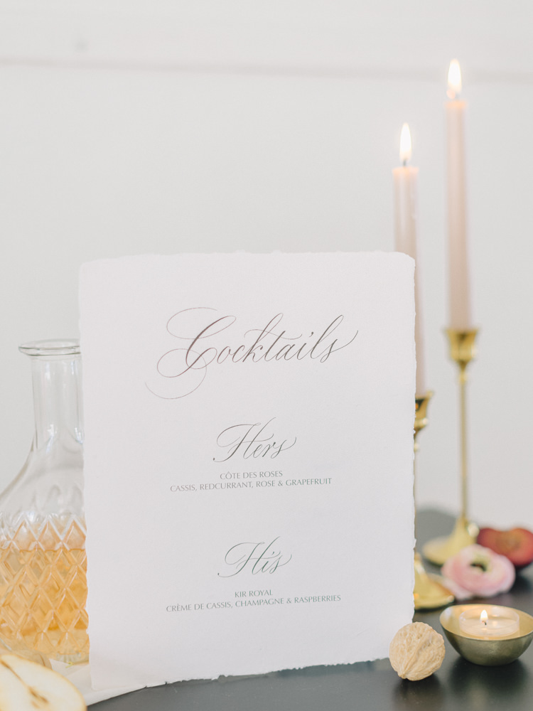 Simple cocktail list sits on a table with candles at a wedding in Montreal